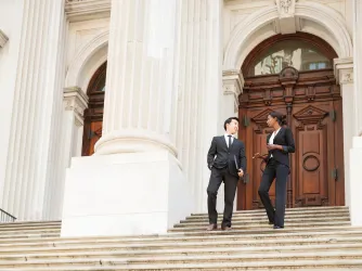 Man and woman dressed in suits walking down steps of a courthouse building